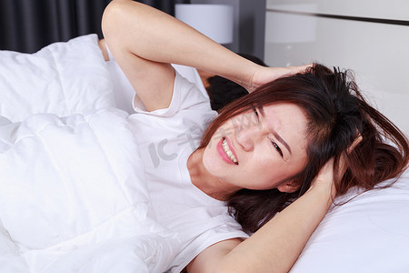 女人在床上失眠，在卧室里有偏头痛、压力、失眠、宿醉