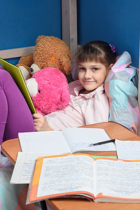 女孩微笑着看着框架，拿着平板电脑，在她的谎言教科书和笔记本前