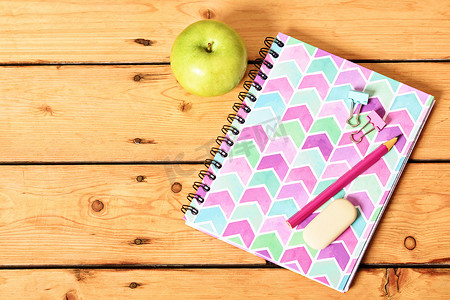 木制背景上的粉色笔记本和苹果