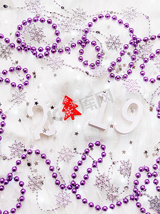 圣诞节和新年背景与数字 2019，红杉树，银色和紫色装饰品和灯泡。
