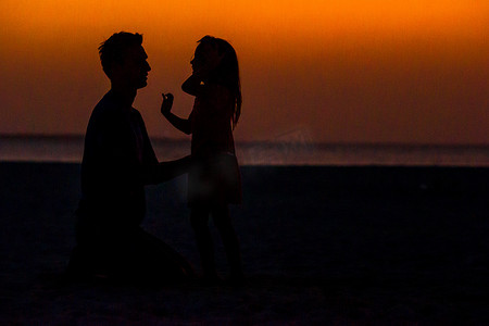 夕阳下的人摄影照片_海滩夕阳下的小女孩和爸爸剪影