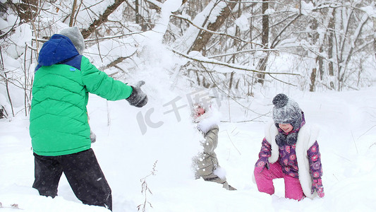 两个小女孩和一个小男孩在冬季森林的雪地里玩耍。