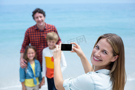 快乐的妈妈在海滩上给家人拍照