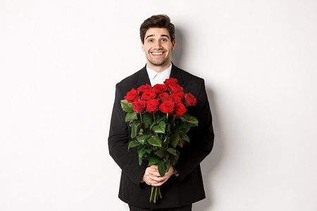 身穿黑色西装、手持玫瑰花、微笑、站在白色背景下的英俊男子的形象
