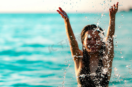 身着黑色泳装的快乐亚洲年轻女性放松并享受假期