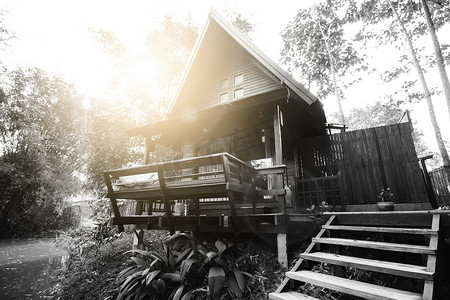 泰式房屋由河边的硬木制成，黑白相间，阳光和镜头光晕。