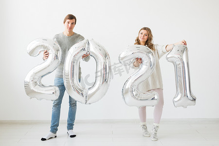 假期、节日和派对概念 — 幸福的情侣拿着白色背景的 2021 年银色气球。
