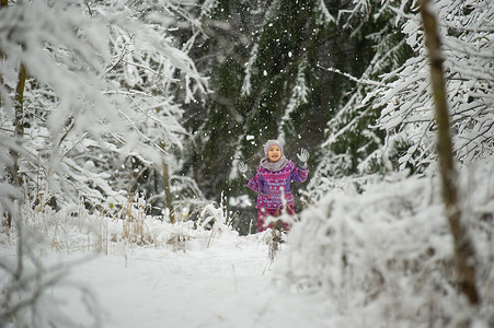 冬天，一个穿着紫色衣服的小女孩穿过白雪覆盖的森林
