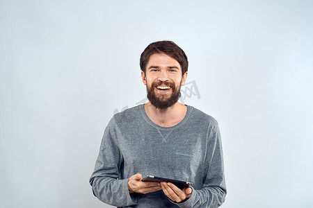 一个留着胡子的男人，手里拿着平板电脑，灰色夹克技术互联网光背景