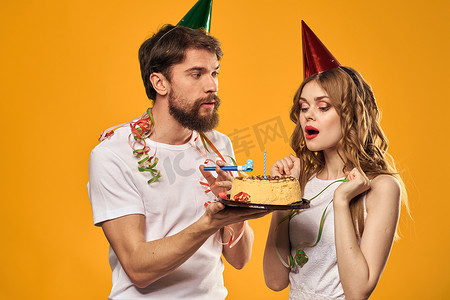 男女生日喜庆蛋糕黄色背景和头上的帽子
