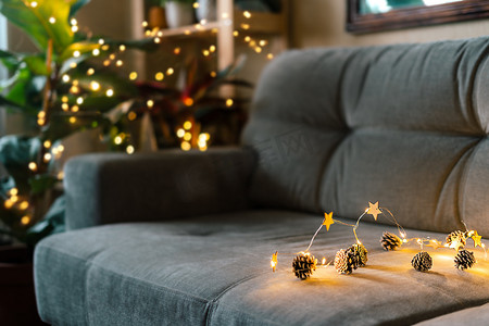 圣诞节自然生态装饰、松果、舒适家灰色沙发背景上的灯光。