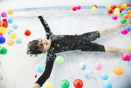 水池玩具摄影照片_男孩在小游泳池玩具中玩彩球 — 水池玩具概念中的快乐男孩