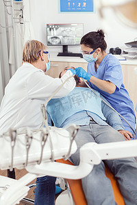 正牙医生老年妇女对病人进行口腔治疗