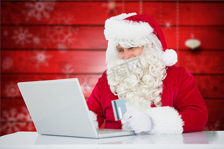 圣诞老人在笔记本电脑上用信用卡在线购物