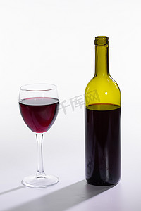 红酒瓶在白色背景上倒玻璃