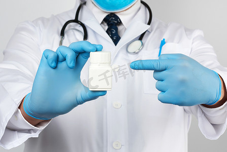 乳汁摄影照片_一件白色医疗外套和蓝色乳汁手套的男性医生拿着