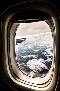 在平静的阳光明媚的日子里，从飞机窗外望去，蓝天白云，下面的土地形成美丽的旅行背景照片图像。