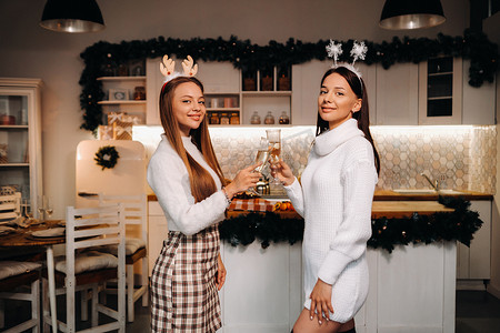 圣诞节时，两个女孩在舒适的家庭环境中，手里拿着香槟。