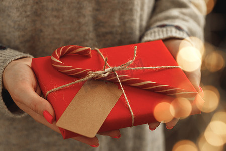 茶叶包装包装盒摄影照片_穿毛衣的女手拿着包装好的圣诞礼物