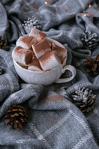 舒适的冬季毛衣背景上配有棉花糖和可可粉的可可饮料。