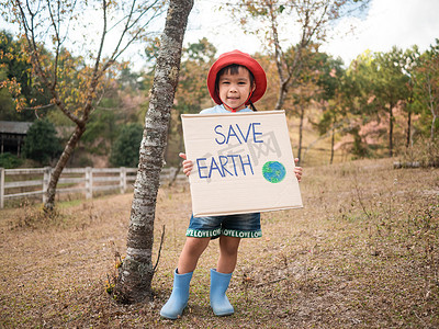 拿着“拯救地球”海报的小女孩展示了抗议森林塑料污染的标志。