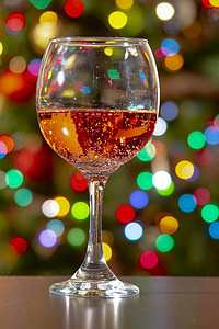 倾倒的酒杯摄影照片_甜果味起泡玫瑰酒，酒杯上有气泡，彩灯