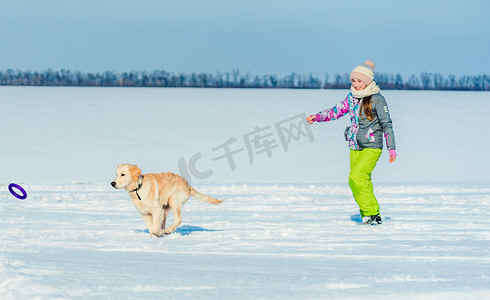 雪地里牵着狗奔跑的女孩