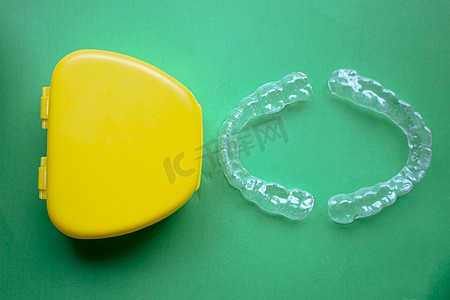 绿色护牙摄影照片_右边带黄色外壳的护齿套，背景为绿色
