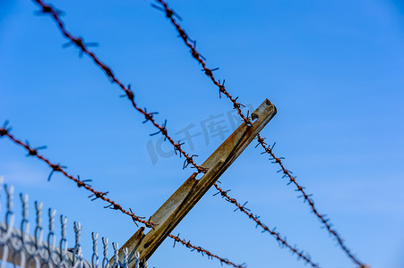 有边界摄影照片_专注于蓝天映衬的生锈铁丝网。