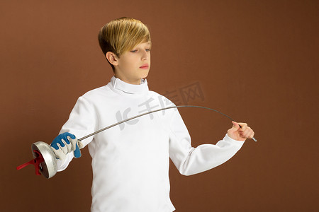 穿着白色击剑服装与剑杆的男孩击剑手