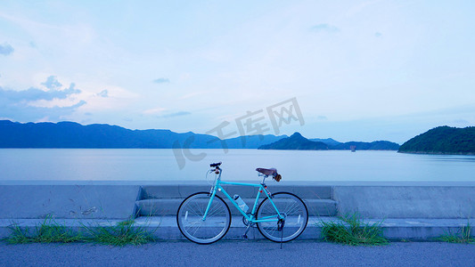 带皮座和包的自行车复古风格傍晚的自行车、路、云和湖
