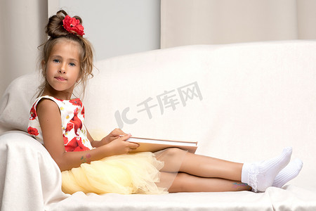 一个小女孩坐在沙发上看书。