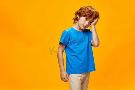 浓度摄影照片_红发男孩抱着头蓝色T恤，情绪被裁剪