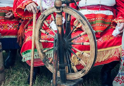 旧木纺车和身着民族服饰的女人。