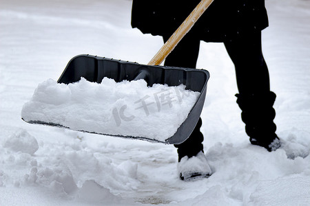 在冬天，女性用装满雪的铲子铲雪。