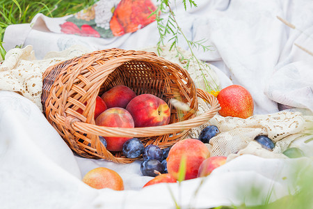 花边织物上放着桃子、李子和梨子的水果篮。