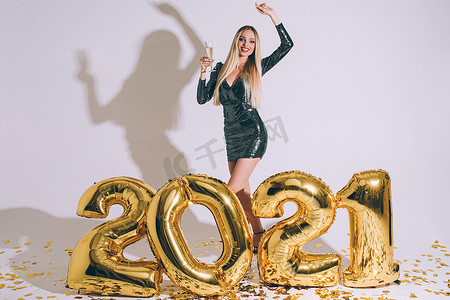 漂亮的金发女郎，带着饮料和 2021 年新年气球。