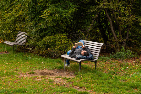 秋季保健摄影照片_2020 年秋季，捷克共和国冬季开始，由于 COVID-19 爆发，隔离期间，布拉格 6 日，一名男子躺在长凳上看书