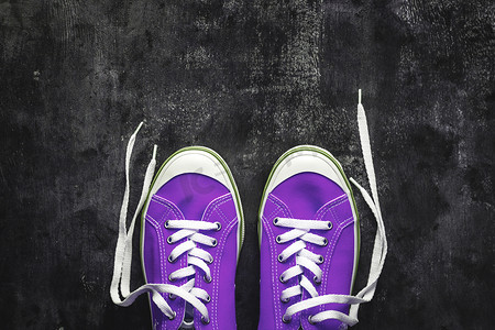紫色-粉红色-淡紫色运动鞋，在深色混凝土背景上系有解开的鞋带。