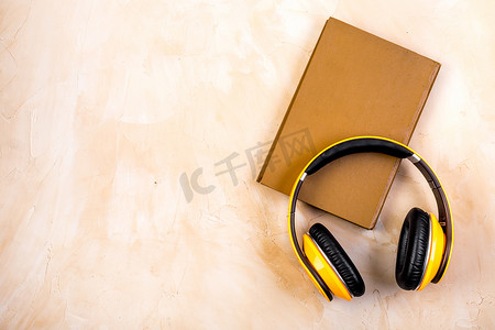 米色桌子上带耳机的有声读物概念，来自上方的复制空间