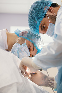 两名身穿蓝色长袍的外科医生在手术室进行手术