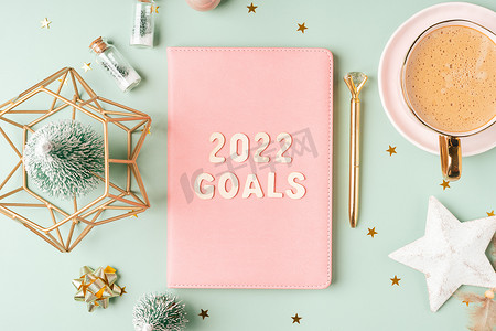 顶视图桌面圣诞粉色记事本，上面写着 2022 年目标字母文本。