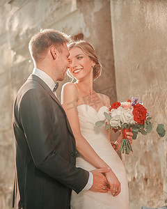 幸福的新婚夫妇站在古城堡的墙边