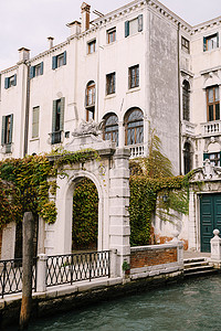 建筑美丽的石拱形入口、绿色的门和经典的威尼斯窗户。