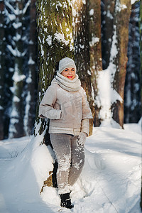 冬天森林里穿着灰色衣服的女人的肖像。新年白雪覆盖的森林里的女孩。