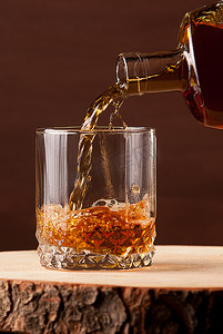 饮料瓶摄影照片_在木桌，棕色背景上的威士忌酒杯