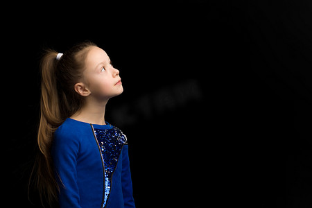 一个沉思的小女孩的侧面肖像。在黑色背景上