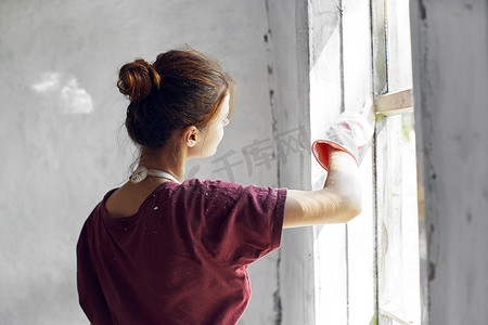 穿白围裙的女人在房屋室内装修中画窗户