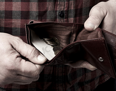 开店预算摄影照片_男人拿着一个开着的棕色皮夹，上面印着乌克兰格里夫纳币