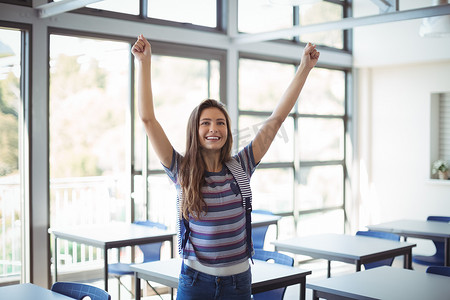 女学生站立摄影照片_兴奋的女学生双臂站立在教室里